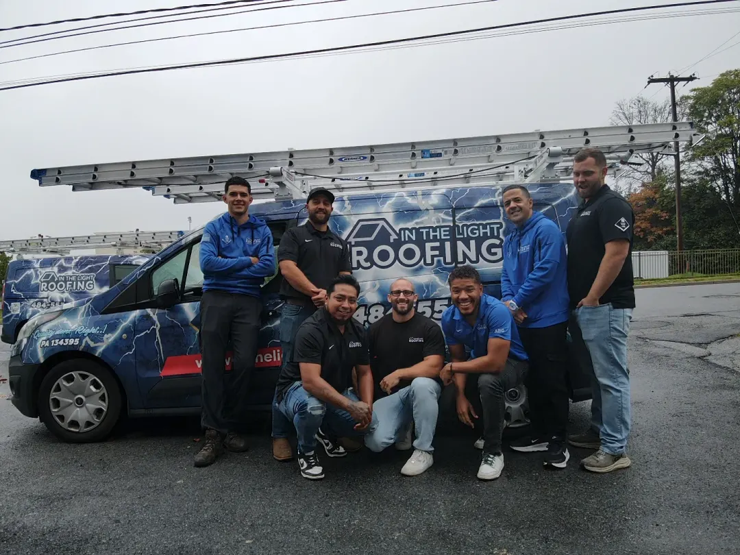 The In The Light Roofing crew standing in front of one of the company vans