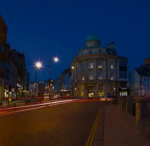 Northampton service area: a domed corner building on a city street at night, car light trails on the road