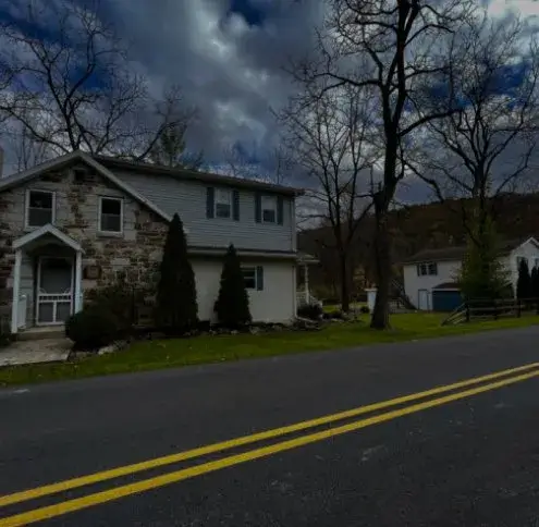 Walnutport service area: a stone and siding two storey house on a rural road under a stormy sky