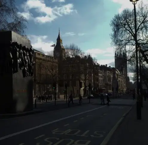 Whitehall service area: a sunlit street of ornate stone buildings running toward a Gothic clock tower