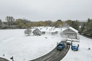 Crew shoveling snow from roof during roof repairs before first snow in Northampton